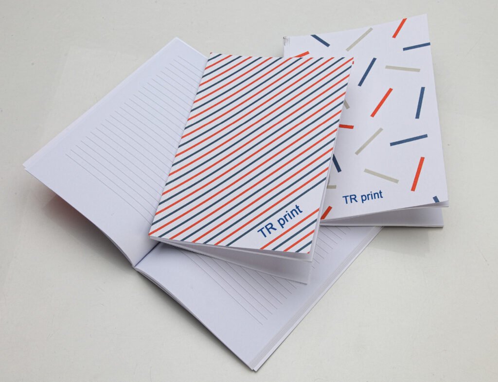 1 open and 2 closed paperback notebooks showing different full printed covers