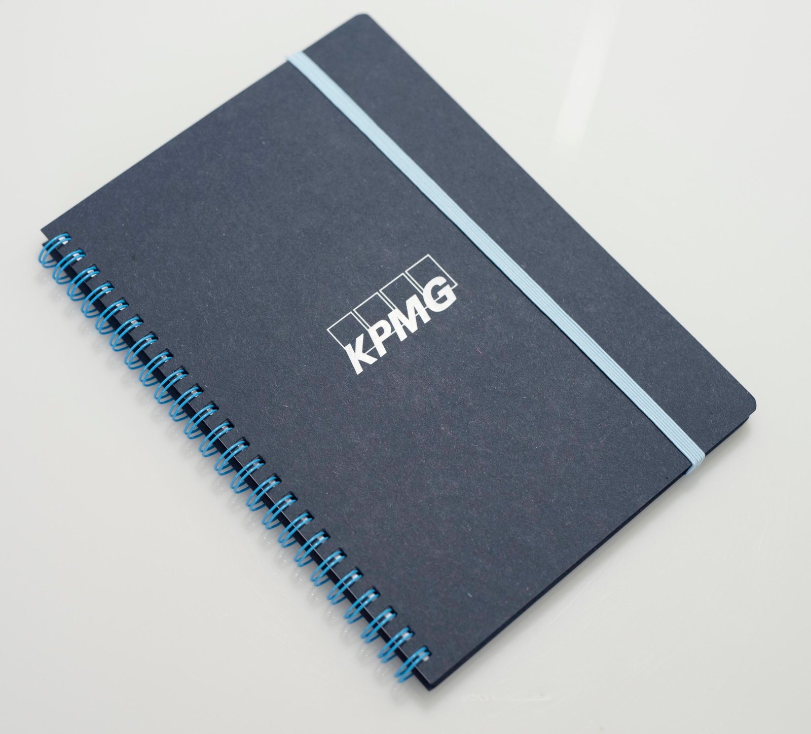 Blue cover notebook with wire-O in blue a, logo in white and elastic band