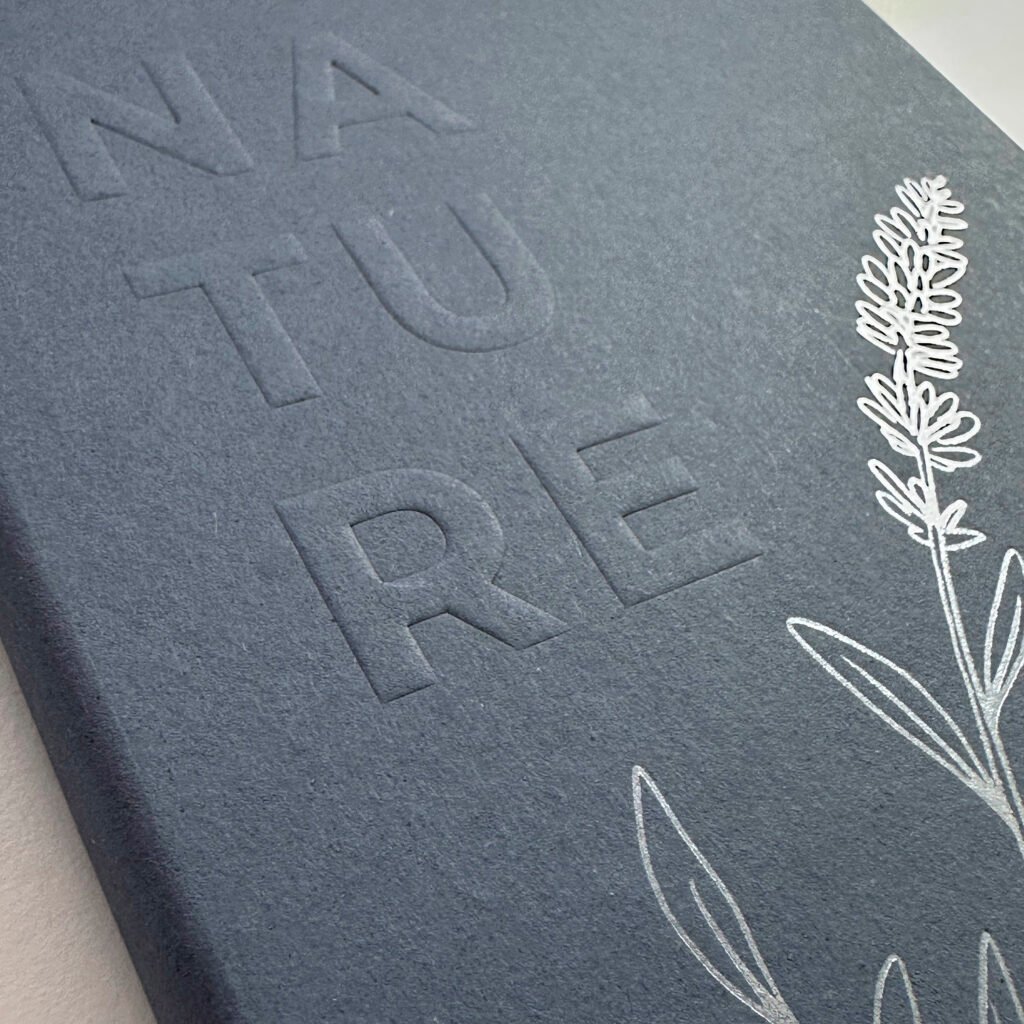 Close up notebook cover in blue Green Mood cardboard with relief logo and silver hot print